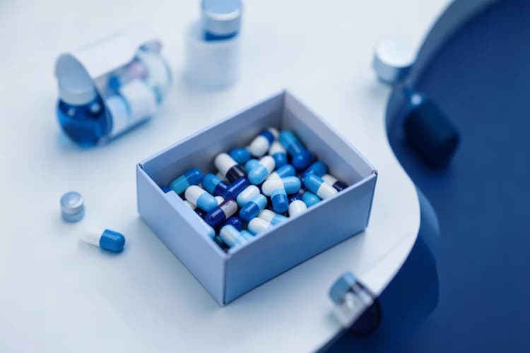 Caixa de pílulas e frascos de medicamentos sobre uma mesa, sugerindo tratamento médico.