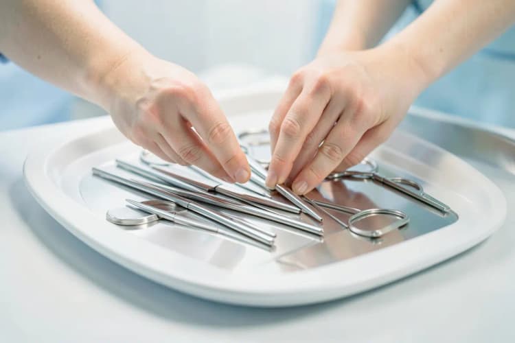 Mãos de um profissional de saúde preparando equipamento médico esterilizado.