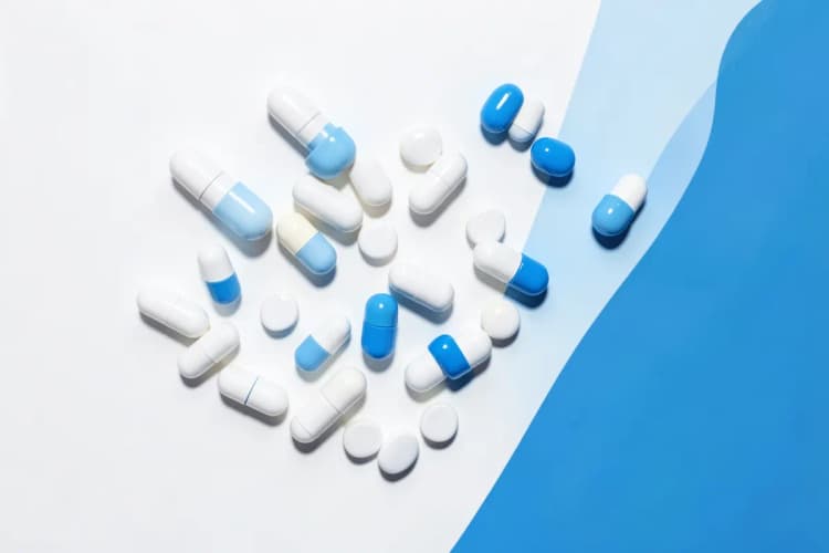 Pílulas e cápsulas de medicamentos anti-inflamatórios em uma superfície branca.