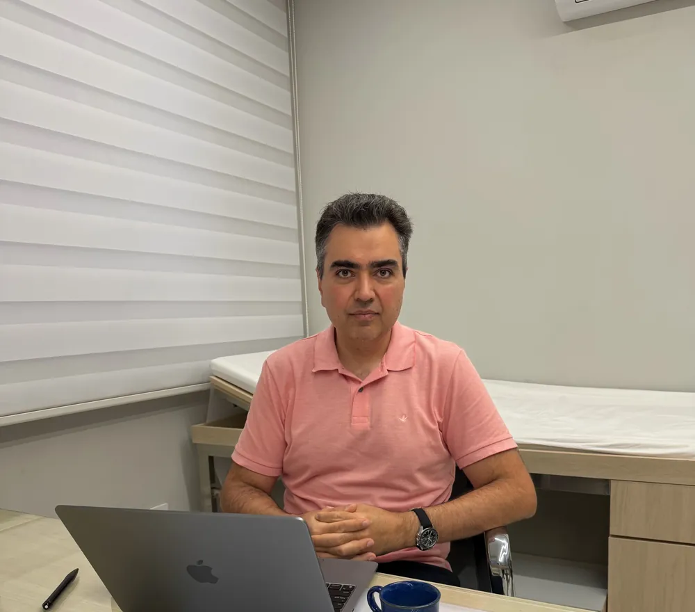 Dr. Ruston Louback, urologista, sentado à mesa em seu consultório